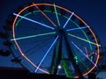 A luminous Ferris wheel is located against the background of the evening sky Royalty Free Stock Photo