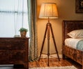 A luminous floor lamp with a wooden tripod stand and lampshade creates coziness in the bedroom