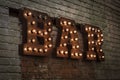 Luminous letters BAR. Volumetric letters from rusty metal on a brick wall with a garland Royalty Free Stock Photo