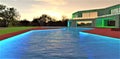 Luminous surface of the stunning swimming pool in front of the entry with illuminated steps to the suburban estate built in the Royalty Free Stock Photo