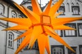 Luminous yellow Christmas star, close-up view in front of a grey building facade