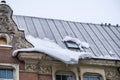 A lump of snow and ice on the edge of the roof of the house. Thaw, chalking snow danger in the city. Royalty Free Stock Photo