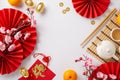Top view fans, tea ceremony set, coins, sycee, lucky red envelopes, dragon charm decor, fruits, sakura on white backdrop Royalty Free Stock Photo