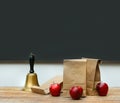 Lunch bags with apples and school bell on desk