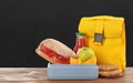 Lunch box with appetizing food and bag on wooden table near blackboard Royalty Free Stock Photo