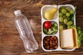 Lunch box with appetizing food and bottle of water on wooden table Royalty Free Stock Photo