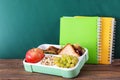 Lunch box with appetizing food and notebooks on wooden table Royalty Free Stock Photo