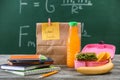 Lunch box with appetizing food and stationery on table in classroom Royalty Free Stock Photo