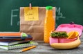 Lunch box with appetizing food and stationery on table in classroom Royalty Free Stock Photo