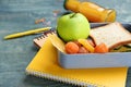 Lunch box with different food and stationery on table Royalty Free Stock Photo