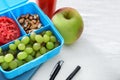 Lunch box with appetizing food and stationery on white wooden table Royalty Free Stock Photo