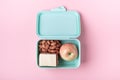 Lunch box with apple, sandwich and almond on pink background Back to school concept with copy space for text