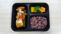 Lunch box with rice berry, vegetables, chicken, pumpkin, carrot, tomato, potato, block kerry in the black lunch box, healthy food