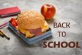 Lunch box with tasty sandwich and stationery on grey table Royalty Free Stock Photo