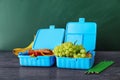 Lunch boxes with appetizing food and pencils on wooden table Royalty Free Stock Photo