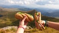 Lunch break in Austrian Alps. Two hands holding sandwiches with the view on high Alps. There are endless mountain chains Royalty Free Stock Photo