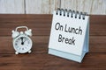 On lunch break text on white table calendar with alarm clock pointing at 12pm. Office and business concept Royalty Free Stock Photo