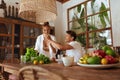 Lunch. Couple Cooking At Kitchen. Happy Man Feeding Beautiful Woman While She Preparing Fresh Organic Vegetables.