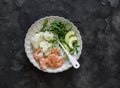 Lunch diet - rice, shrimp, boiled cauliflower, arugula, avocado in one plate on a dark background, top view