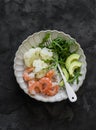Lunch diet - rice, shrimp, boiled cauliflower, arugula, avocado in one plate on a dark background, top view Royalty Free Stock Photo