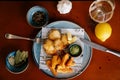 Lunch with fried potatoes, fish nuggets, green sauce, garlic, bay leaf and lemon on red table