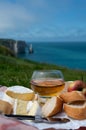 Lunch on green grass fields on chalk cliffs of Etretat, french cheese camembert and apple cider drink with Atlantic ocean on
