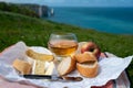 Lunch on green grass fields on chalk cliffs of Etretat, french cheese camembert and apple cider drink with Atlantic ocean on