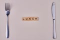 Lunch inscription from wooden blocks. Fork and knife on white background. Royalty Free Stock Photo