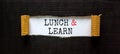 Lunch and learn symbol. Words `Lunch and learn` appearing behind torn black paper. Beautiful black background. Business,