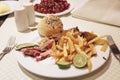 Lunch at restaurant serving portion of french fries, meats, fresh cut cucumbers