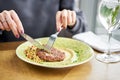 Lunch in a restaurant, a woman cuts delicious Beefsteak marbled beef, served with bulgur and smoked onion cream Royalty Free Stock Photo