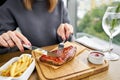 Lunch in a restaurant, a woman cuts Delicious Pork ribs. Full rack of ribs BBQ on wooden plate with french fries and Royalty Free Stock Photo