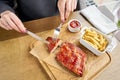 Lunch in a restaurant, a woman cuts Delicious Pork ribs. Full rack of ribs BBQ on wooden plate with french fries and Royalty Free Stock Photo