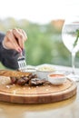 Lunch in a restaurant, a woman cuts Pieces of liver cooked on the grill. Serving on a wooden Board. Barbecue restaurant Royalty Free Stock Photo