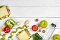 Lunch. Sandwich and fresh vegetables, bottle of water, nuts and fruits on white wooden background. Healthy eating Royalty Free Stock Photo