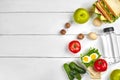 Lunch. Sandwich and fresh vegetables, bottle of water, nuts and fruits on white wooden background. Healthy eating Royalty Free Stock Photo