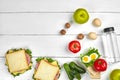 Lunch. Sandwich and fresh vegetables, bottle of water, nuts and fruits on white wooden background. Healthy eating Royalty Free Stock Photo