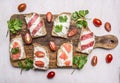 Lunch with sandwiches with salami and smoked red fish with parsley leaves and curd cheese wooden rustic background top view clo