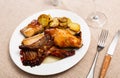 Lunch is served on plate - pieces of young rabbit baked with slice of potato. Close-up