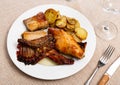 Lunch is served on plate - pieces of young rabbit baked with slice of potato. Close-up