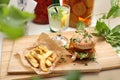 Lunch set. Cheeseburger, potato fries and lemonade on a wooden tray, cutting board. Plant-based meal, horizontal view.