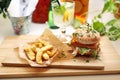 Lunch set. Vegan cheeseburger, potato fries and lemonade on a wooden cutting board. Plant-based meal, horizontal view.