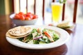 lunch setting: greek salad plate next to pita bread and tzatziki