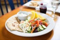 lunch setting: greek salad plate next to pita bread and tzatziki