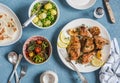 Lunch table. Lemon thyme baked chicken, boiled potatoes with green peas, salad with lentils and tomatoes, flatbread on a blue back