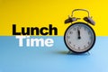 LUNCH TIME inscription written on Alarm Clock on blue yellow background