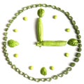 Lunch time.Vegetarian diet of vegetables in the form of clocks,green onions, Basil and peas isolated on a white background. .
