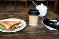 Lunch with triangle sandwich, takeaway coffee and sunglasses on wooden table