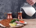 Lunch with Turkish tortilla Lagmajun, a man`s hand pours a Turkish national drink ayran in special dishes