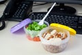 Lunch on work place. Food box container with fresh salad, buckwheat and chicken on the working desk with keyboard. Royalty Free Stock Photo